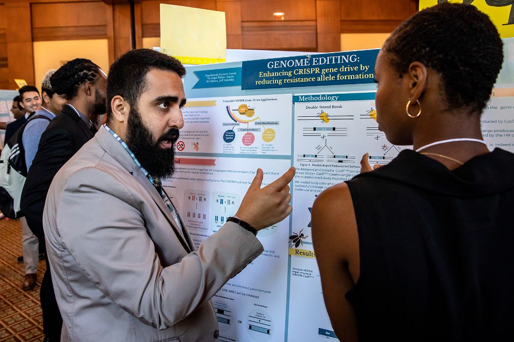 Students with posters at the Summer Undergraduate Pipeline Research Symposium describe their research to attendees.