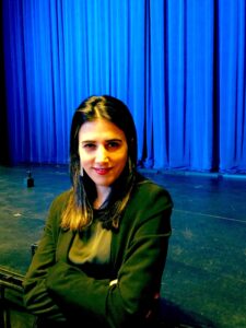 Elena Peña-Argüeso, posing in front of a blue theater curtain.