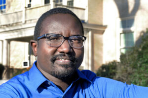 Samuel Akau, wearing glasses and a blue collared shirt