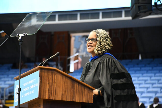 Dr. Meredith Evans in regalia addresses a crowd.