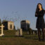 A woman poses in a cemetery with tombstones in the background.