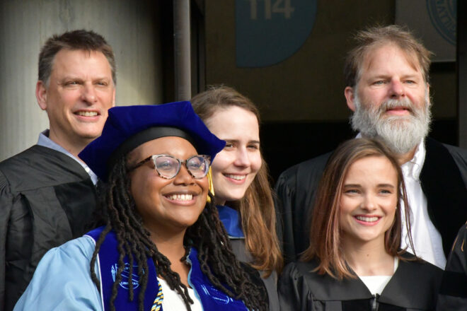 A group of people wearing doctoral regalia smile