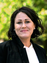 A woman in a black suit poses for a photo.