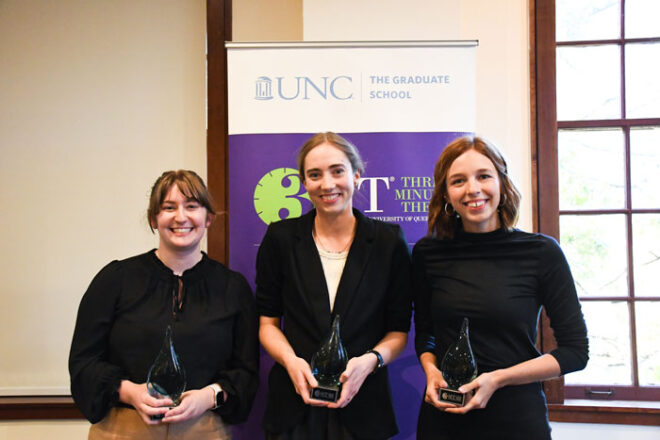 A group of three people pose for a photo while holding awards