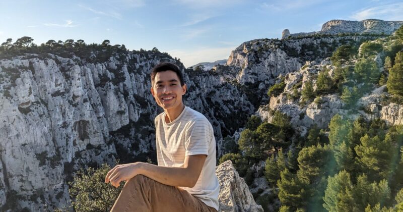 Austin Vo in front of green canyon and rocky cliffs