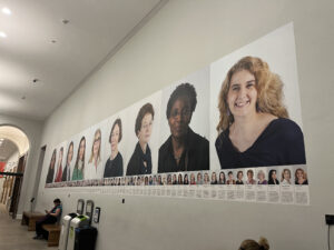 A row of photo portraits of women along a wall.